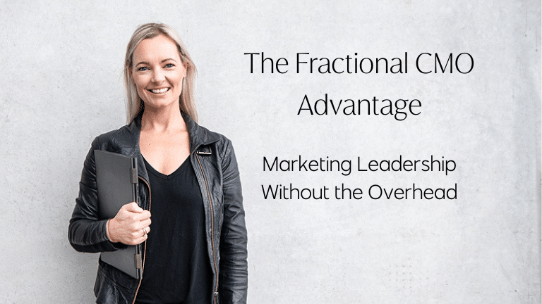 Amanda Roberts from Aligned Media stands with laptop in hand in front of a wall where the text The Fractional CMO Advantage - Marketing Leadership without the overhead